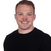 Ung voksen mann med kort hår, bart og sort genser. Smiler og ser rett på kamera. Portrettfoto. Hvit bakgrunn. - Klikk for stort bilde